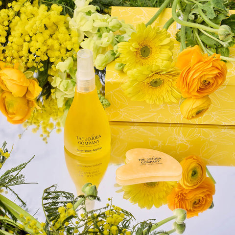 Yellow bottle and soap with floral arrangement on a light blue background.