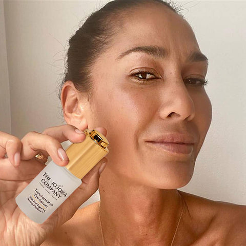 Woman applying skincare product from The Jojoba Company to her face.