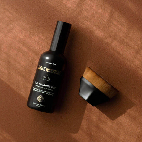 'Three Warriors face tan aqua mist bottle with a brush on a brown background.