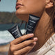 Woman holding skincare products with a beach background