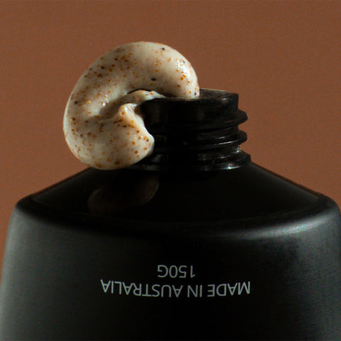 Black container with a dollop of cream on top against a brown background.