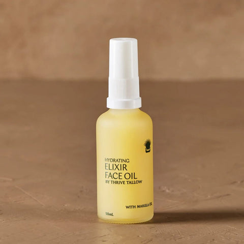 Yellow bottle of 'Hydrating Elixir Face Oil' by Thrive Tallow on a brown background.