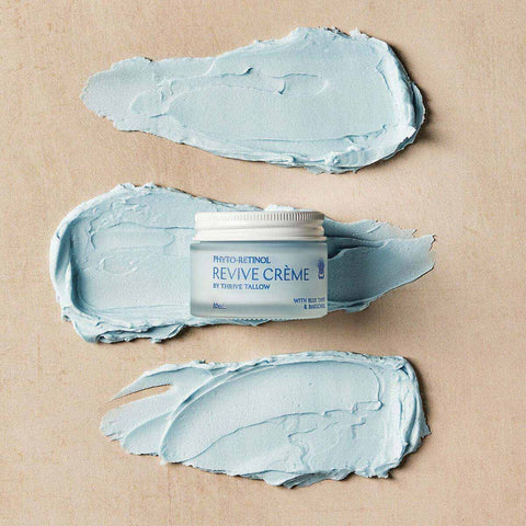 Revive Creme jar surrounded by smears of light blue cream on a beige background.