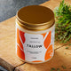 Tallow container with gold lid on a wooden surface.