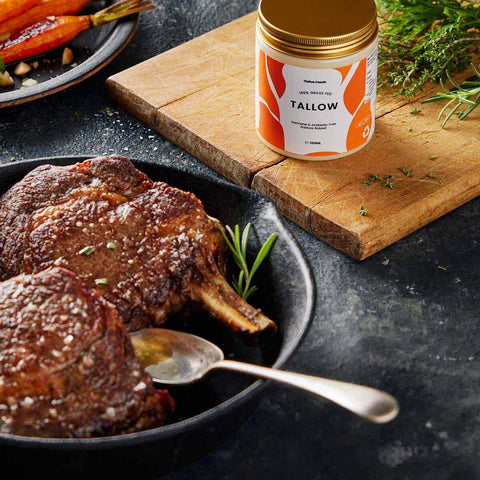 Served beef with a can of tallow on a wooden board, surrounded by herbs.