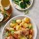 Bowl of roasted potatoes with chicken and green beans on a grey surface.
