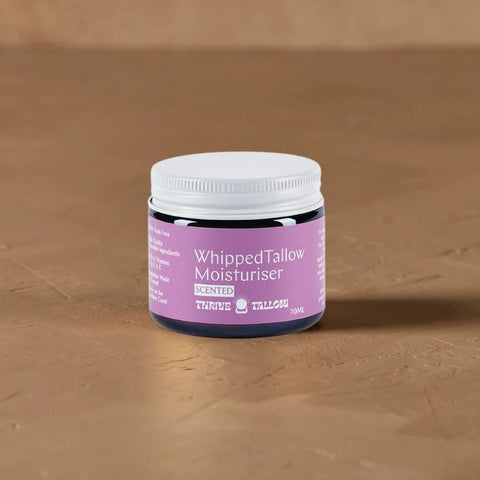 Jar of whipped tallow moisturiser with a purple label on a brown surface.