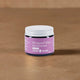 Jar of whipped tallow moisturiser with a purple label on a brown surface.