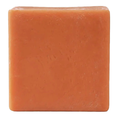A single square bar of orange soap with a textured surface, isolated on a white background.