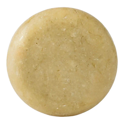 A round, solid bar of soap with a textured surface in a light tan colour, isolated on a white background.