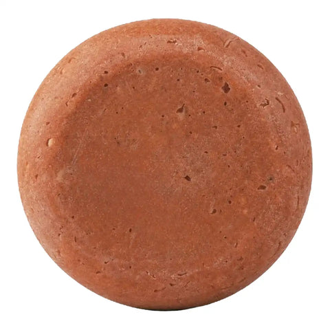 A round terracotta-coloured soap bar with a textured surface, isolated on a white background.