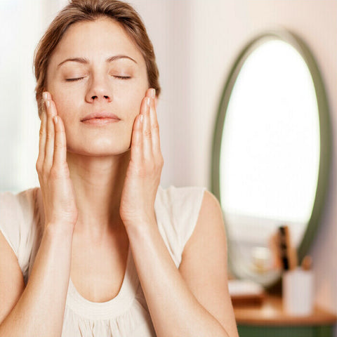 Woman massaging face oil into her cheeks. 