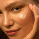 Close-up of a person applying skin food light cream to their face